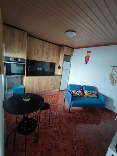 a living room with a blue couch and a table at Recanto do Oeste in São Pedro da Cadeira