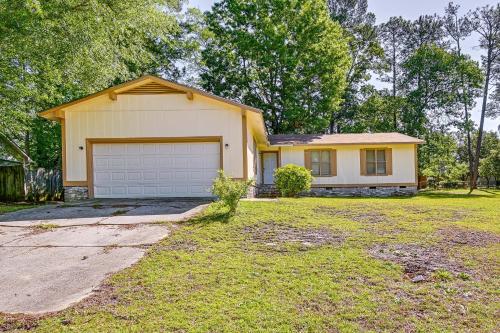 a yellow house with a garage in a yard at Fayetteville Vacation Rental with Yard! in Fort Bragg