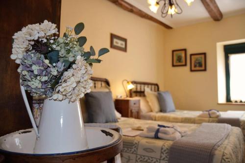 un jarrón con flores sobre una mesa en la sala de estar en Casa Rural El Corredor en Cabornera de Gordón en Cabornera