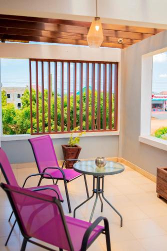 a patio with purple chairs and a glass table at Lovely 4 Bedroom Solar Powered House with CCTV and Unlimited WiFi near Devtraco Court Community 25 Tema in Tema
