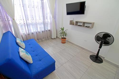 a living room with a blue couch and a fan at Apartahotel La Villa Santa fe de Antioquia in Santa Fe de Antioquia