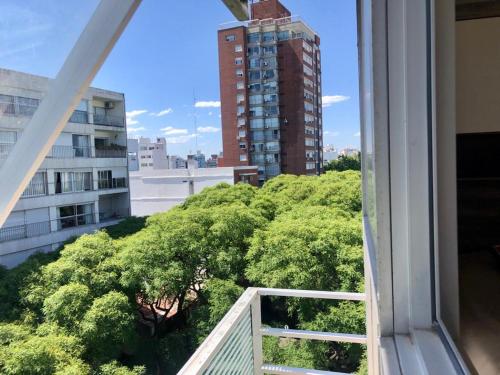 una ventana con vistas a los árboles y a un edificio en Mono en piso 8 - Punta Carretas, en Montevideo