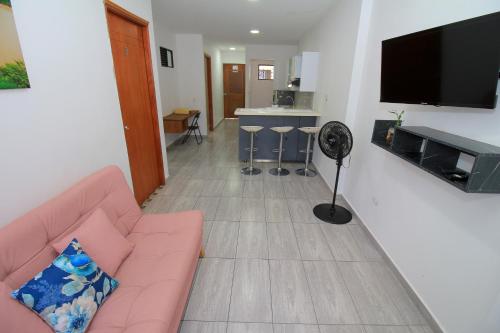 a living room with a pink couch and a flat screen tv at Apartahotel La Villa Santa fe de Antioquia in Santa Fe de Antioquia