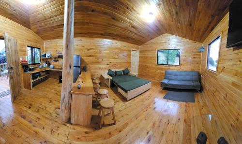 una sala de estar en una cabaña de madera con sofá en Cabaña en Vivero, Dota, Jardin en Jardín