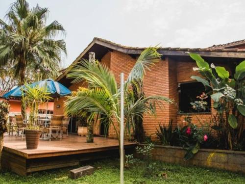 a brick house with a patio and palm trees at Hostel Trópico de Capricórnio - Vermelha do Centro in Ubatuba