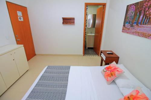 a bedroom with a white bed and a hallway at Apartahotel La Villa Santa fe de Antioquia in Santa Fe de Antioquia