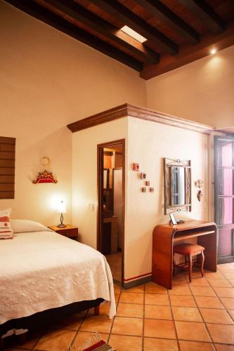 a bedroom with a bed and a desk and a mirror at Hotel Casa Pereyra in Oaxaca City