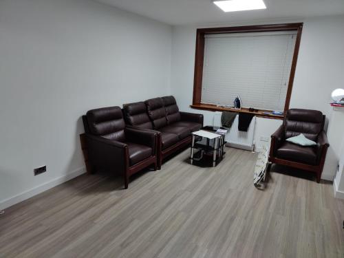 una sala de espera con 2 sillas de cuero y una ventana en Room for rent, en Aberdeen