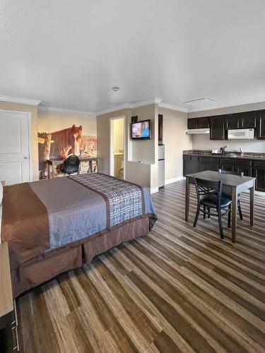 a bedroom with a bed and a table and a kitchen at Rodeo Lodge in Clovis