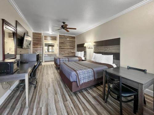 a hotel room with two beds and a desk at Rodeo Lodge in Clovis