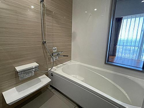 a bathroom with a bath tub and a window at Jisco Hotel Obama Onsen in Obama