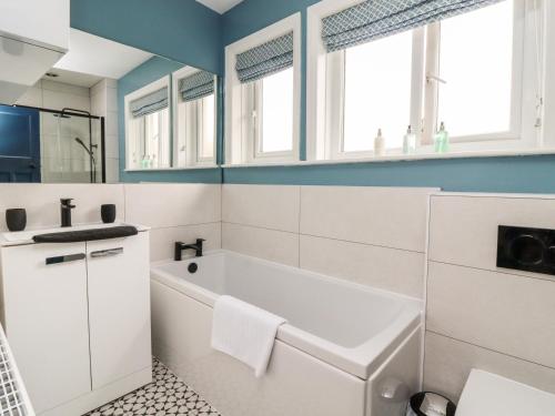 a white bathroom with a tub and a sink at The Kingsway in Ilkley