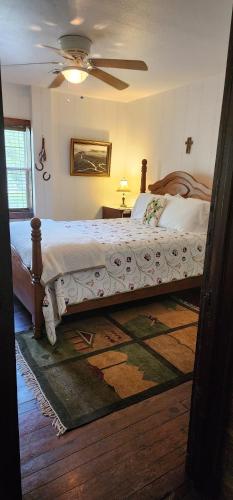 a bedroom with a large bed and a ceiling fan at Hootie Creek Guest House in Talihina