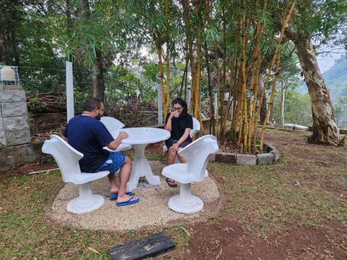 a man and a woman sitting at a white table at Windy Rich Bungalow Belihuloya in Belihul Oya