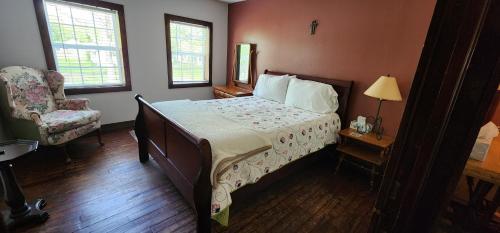 a bedroom with a bed and a chair and a lamp at Hootie Creek Guest House in Talihina