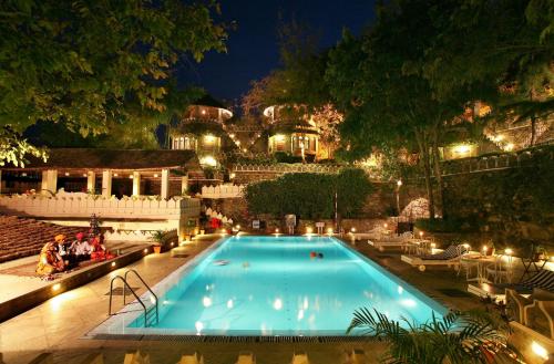 a swimming pool at night with people sitting around it at The Aodhi by HRH Group of Hotels in Kumbhalgarh