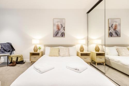 a bedroom with a large white bed and a mirror at KULA South Yarra in Melbourne