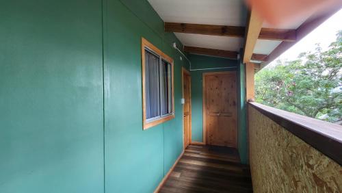 a hallway of a house with a green wall and a window at Cabañas Manuto in Hanga Roa