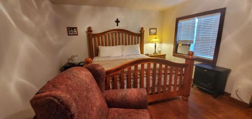 a bedroom with a bed and a chair and a window at Hootie Creek Guest House in Talihina