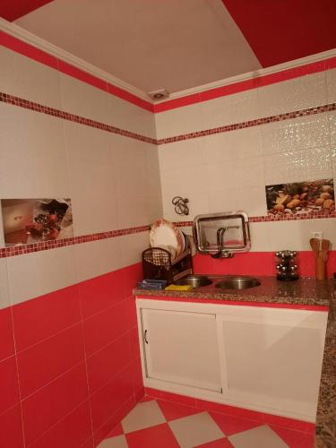 eine Küche mit roten und weißen Wänden und einem Waschbecken in der Unterkunft JERDOUH For FAMILY ONLY in Tétouan