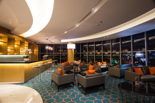 a hotel lobby with chairs and a bar at Hotel Ciputra Cibubur managed by Swiss-Belhotel International in Cibubur