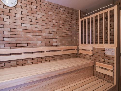 a sauna with wooden benches and a brick wall at REF Kansai Airport by VESSEL HOTELS in Izumi-Sano