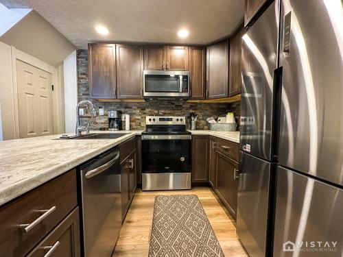 a kitchen with wooden cabinets and a stainless steel refrigerator at Luxury Ski Condo With Hot Tub in Brian Head