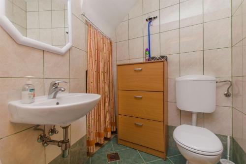 ein Badezimmer mit einem Waschbecken, einem WC und einem Spiegel in der Unterkunft House Stone house in center in Jelsa