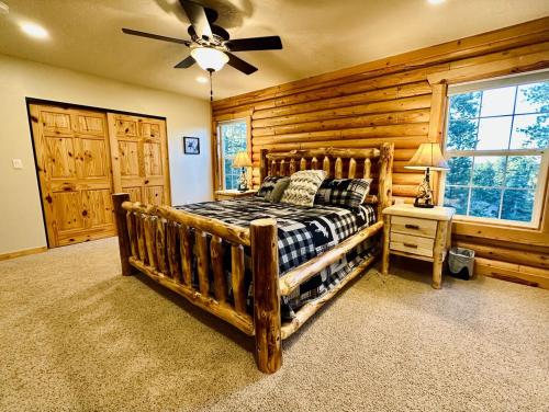 a bedroom with a wooden bed and a ceiling fan at Backwoods Bonanza - Big Cabin With Hot Tub! in Duck Creek Village