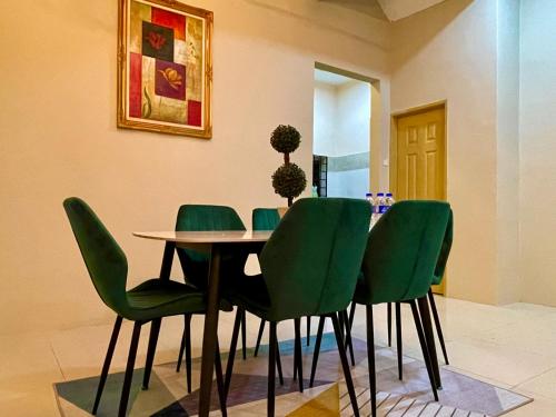 a dining room with green chairs and a table at Homestay D Razak Wakaf Tapai in Marang