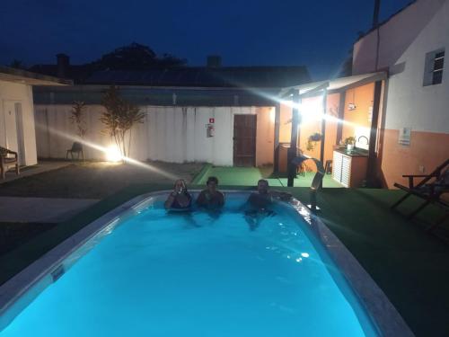 two people sitting in a swimming pool at night at Suíte Luxo Refúgio das Ostras in Guarujá