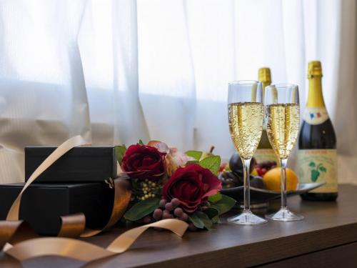 a table with two glasses of champagne and a box of roses at Hotel New Gaea Domemae in Fukuoka