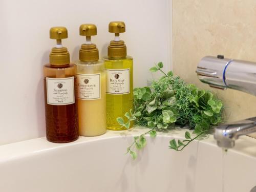 three bottles of essential oils sitting on a shelf in a bathroom at Hotel New Gaea Domemae in Fukuoka