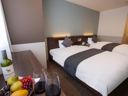 a hotel room with two beds and a table with wine glasses at Hotel New Gaea Domemae in Fukuoka
