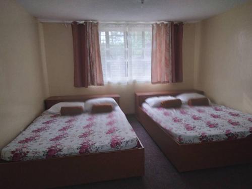 twee bedden in een kleine kamer met een raam bij 4 Bedroom Apartment 15pax Moran in Baguio