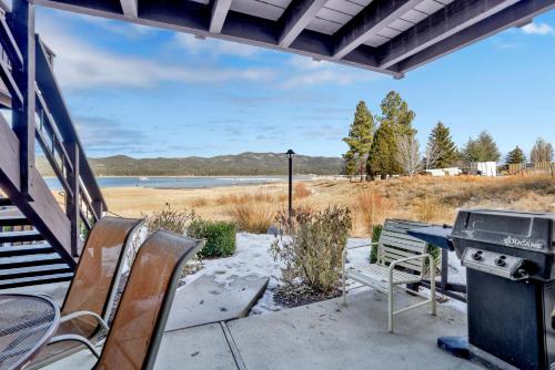 a grill and chairs on a patio with a view of the water at Forest Shores Lake View Condo by Big Bear Vacations Lakefront Village in Big Bear Lake