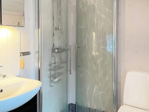 La salle de bains est pourvue d'une douche et d'un lavabo blanc. dans l'établissement Holiday home LJUNGSKILE VI, à Ljungskile