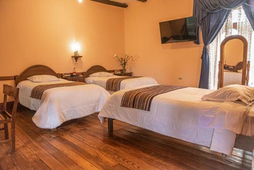 a bedroom with two beds and a tv on the wall at Casona Del Rosario - Plaza de Armas in Chachapoyas