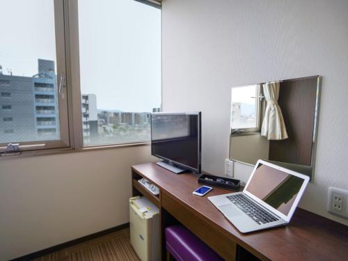 a room with a desk with a laptop and a monitor at Hotel New Gaea Domemae in Fukuoka