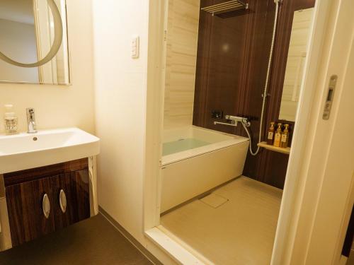 a bathroom with a tub and a sink and a shower at Hotel New Gaea Domemae in Fukuoka