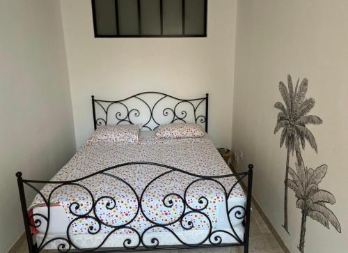 - une chambre avec un lit et une tête de lit en fer forgé dans l'établissement Résidence Raphaël Croisette, à Cannes