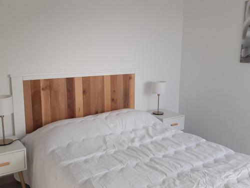 ein weißes Bett mit einem Kopfteil aus Holz im Schlafzimmer in der Unterkunft Appartement Port Leucate, 2 pièces, 4 personnes - FR-1-727-6 in Port Leucate