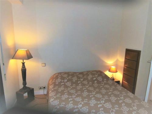 a small bedroom with a bed and a lamp at Appartement Ciboure, 2 pièces, 4 personnes - FR-1-4-673 in Ciboure