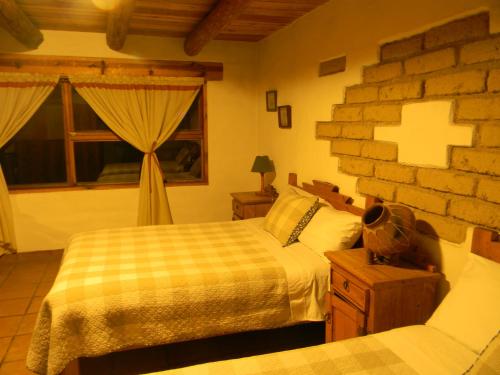 a bedroom with two beds and a brick wall at La Troje de Adobe in Creel