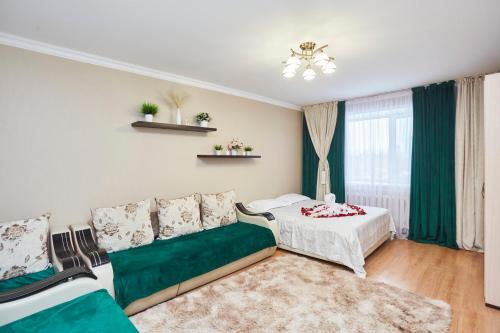 a room with a bed and a couch and a window at Просторная 1ком квартира у Набережной Астаны in Astana
