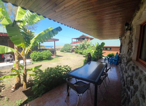 a table and chairs on a patio with a view of a yard at Cabañas Christophe in Hanga Roa