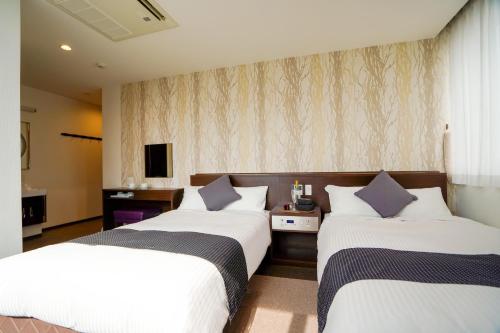a hotel room with two beds and a tv at Hotel New Gaea Domemae in Fukuoka