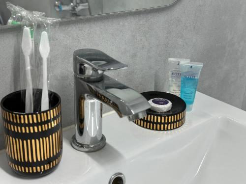 a sink with a faucet and a toothbrush holder at Уютная квартира на ЭКСПО in Prigorodnyy