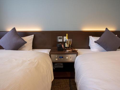 two beds in a hotel room with white sheets and pillows at Hotel New Gaea Domemae in Fukuoka