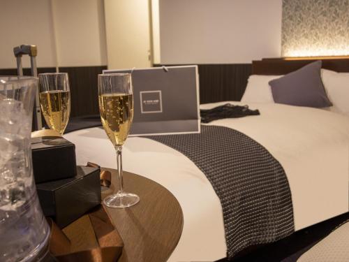 two glasses of champagne on a table next to a bed at Hotel New Gaea Domemae in Fukuoka